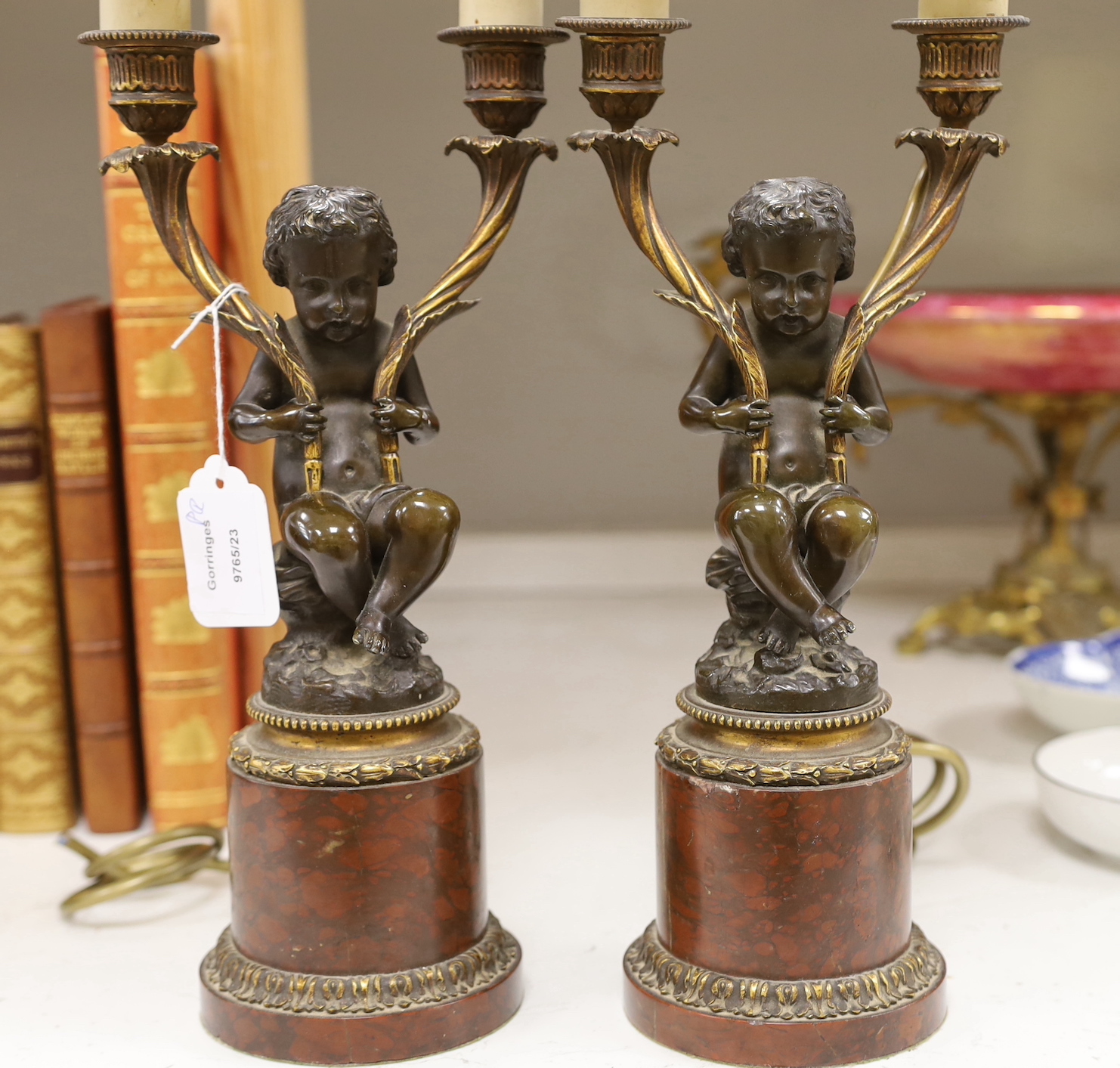 A pair of late 19th century French bronze and ormolu cherub two branch candelabra, converted to lamps, 49cm high including light fitting and bulb